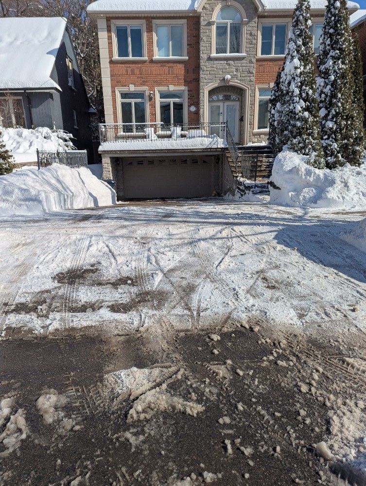 Snow-covered suburban townhouse with a driveway and garage after plowing