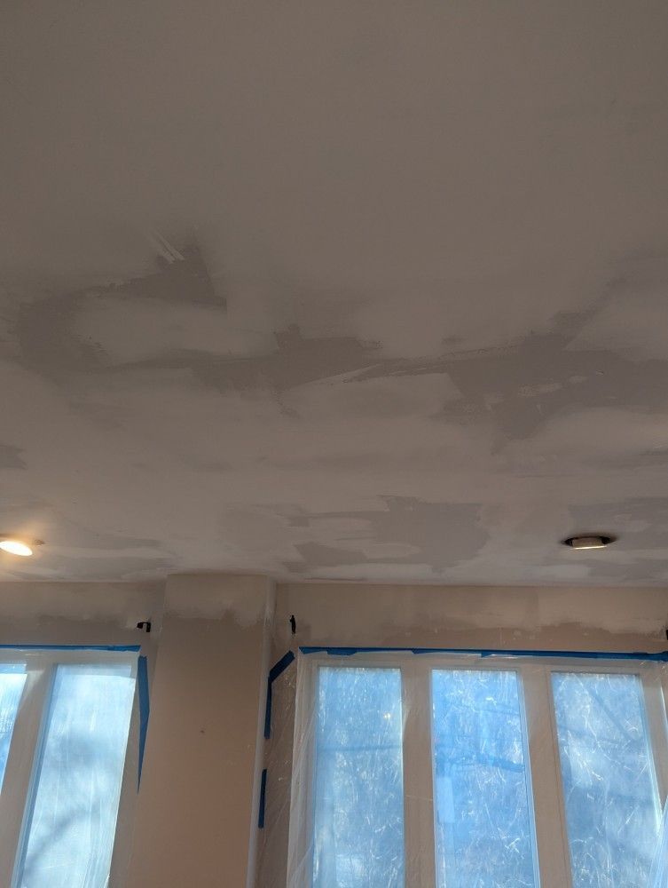 Ceiling with patches of peeling paint above frosted windows in a room