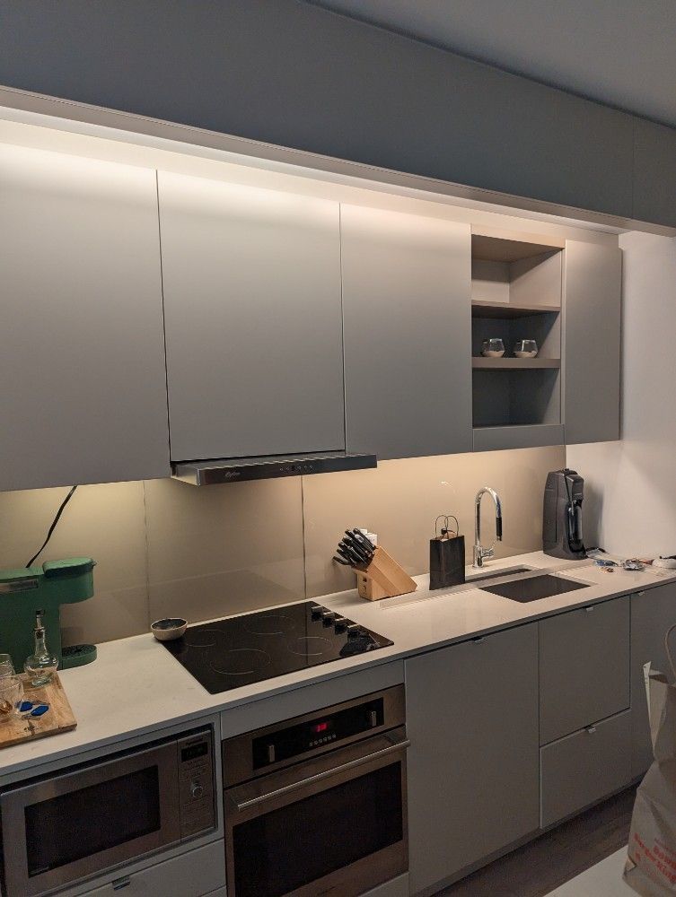 Modern kitchen with gray cabinets, stainless appliances, cooktop, sink, and countertop items