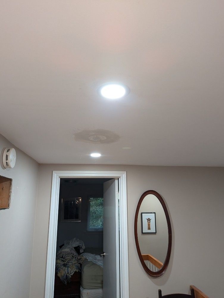 Ceiling lights in a small hallway with a doorway, wall mirror, and glimpse of a bedroom beyond