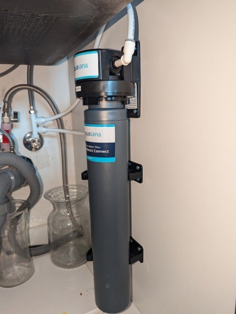 Under-sink water filtration system with blue-and-gray canisters and tubing