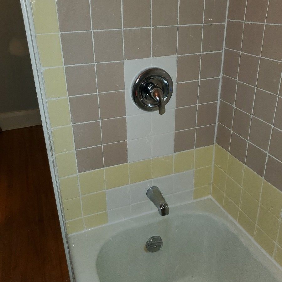 Bathtub shower area with beige tile walls and chrome fixtures above the tub.