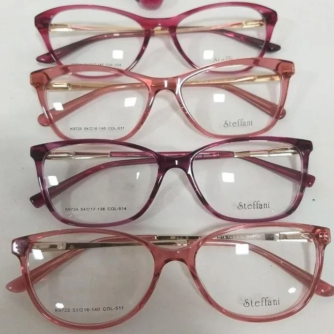 Cuatro pares de gafas con monturas rosas, burdeos y transparentes apiladas verticalmente sobre un fondo blanco.