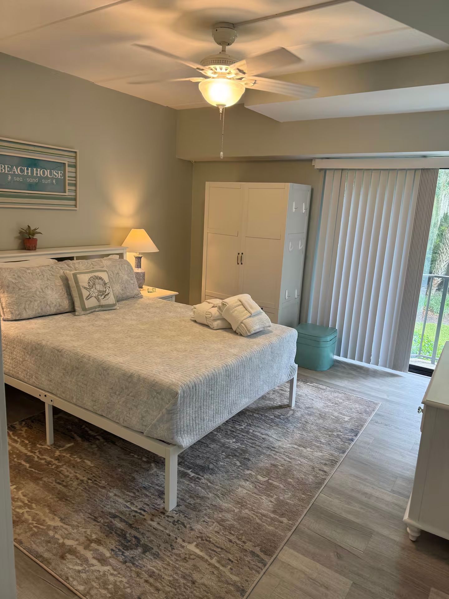 A bright and clean bedroom featuring a queen-sized bed and large windows.