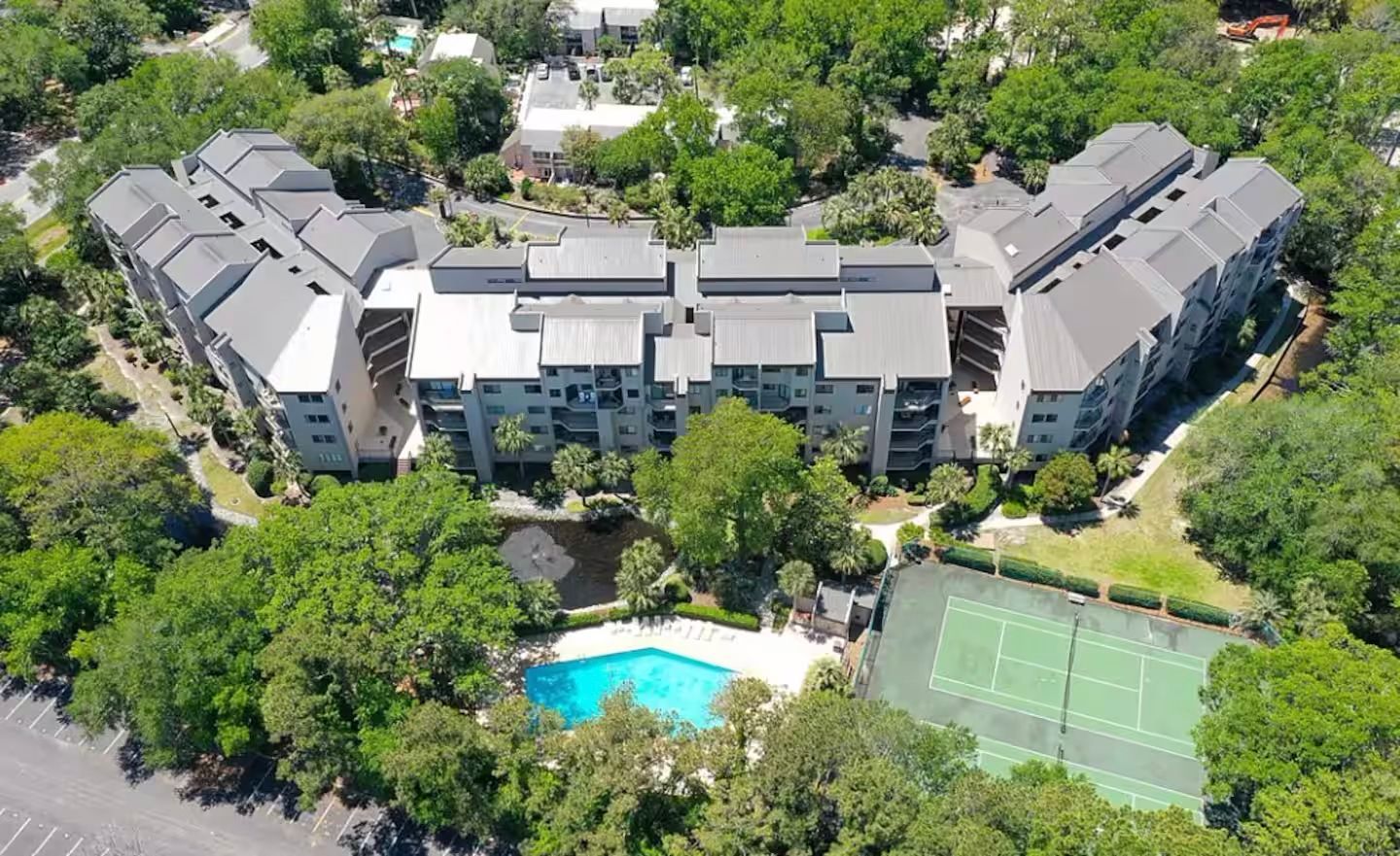 An aerial view of your rental villa complex surrounded by trees and a tennis court.