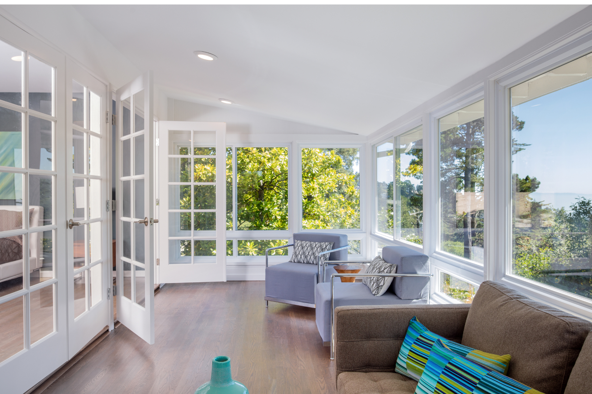 A living room with a couch , chairs , and lots of windows.