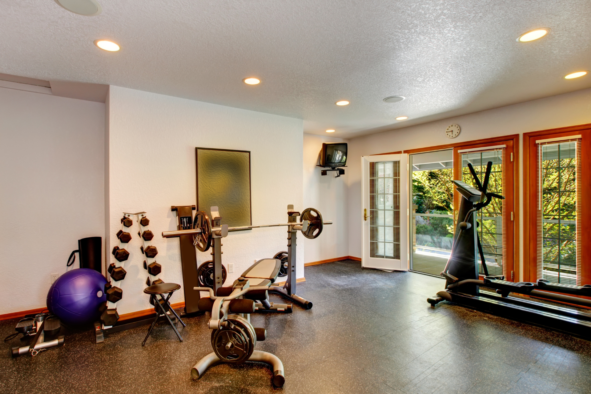 A home gym with a lot of equipment and a purple ball