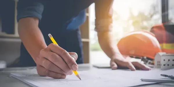 A person is writing on a piece of paper with a pencil.