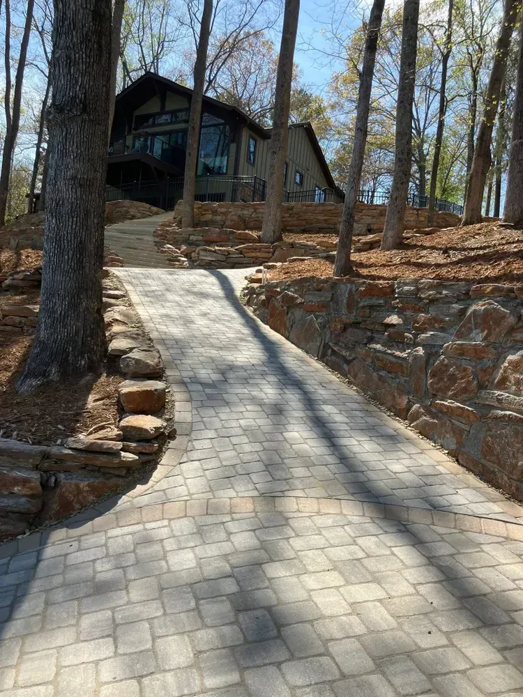 Stone path leading up a wooded hillside to a dark cabin among bare trees