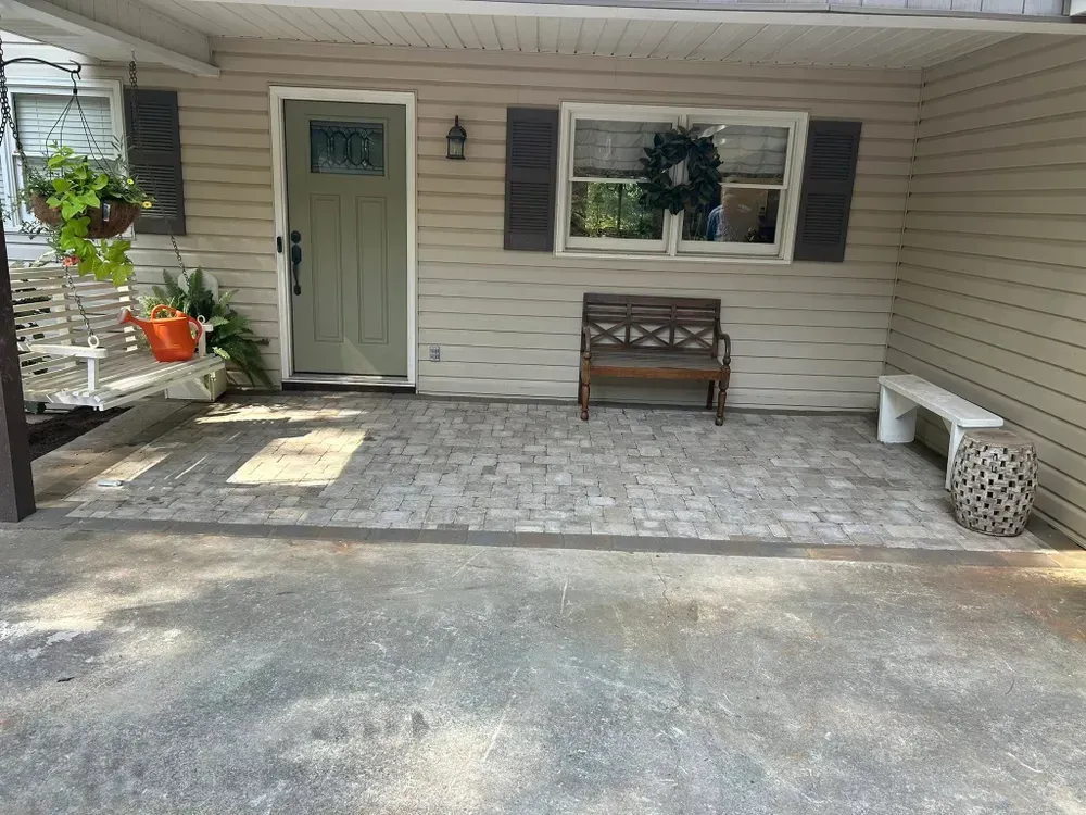 Covered porch with white door, bench, potted plants, and patterned tile flooring