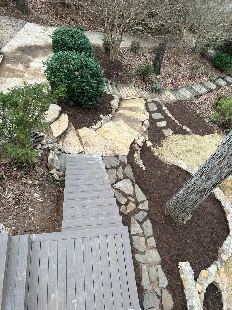Wooden garden walkway with stepping stones, shrubs, mulch, and trees in a landscaped yard