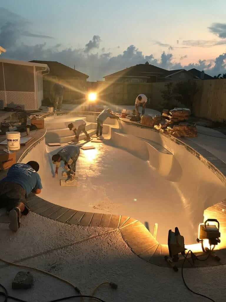 A group of people are working on a swimming pool at night.