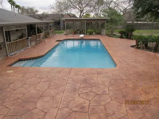 A large swimming pool is in the backyard of a house