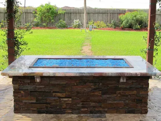 A fire pit is sitting in the middle of a lush green field.