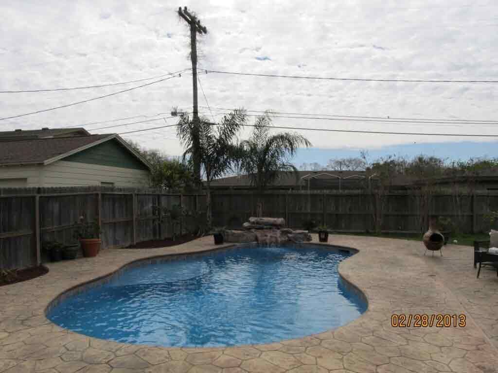 A large swimming pool is in the backyard of a house.
