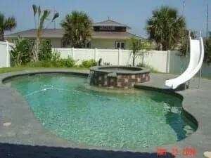 A large swimming pool with a slide in the backyard of a house.