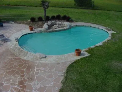 A large swimming pool in the middle of a lush green field.