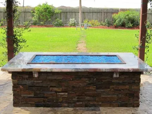 A fire pit is sitting in the middle of a lush green field.