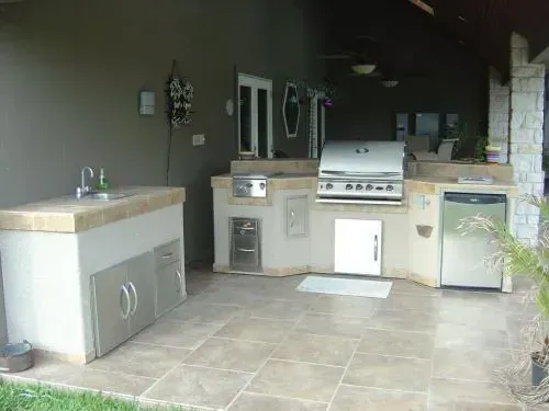 An outdoor kitchen with a grill , sink , and dishwasher.