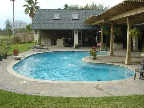 A large swimming pool is in the backyard of a house