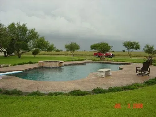 A large swimming pool in the middle of a lush green field