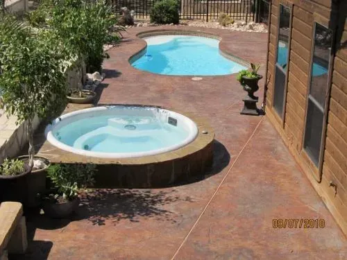 A hot tub sits next to a large swimming pool
