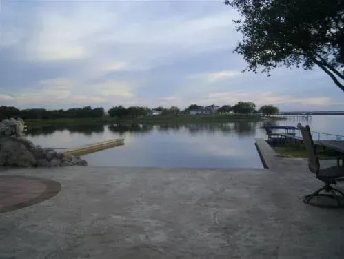 A large body of water with a dock and chairs in the foreground