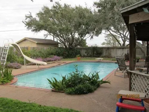 A large swimming pool with a slide in the backyard