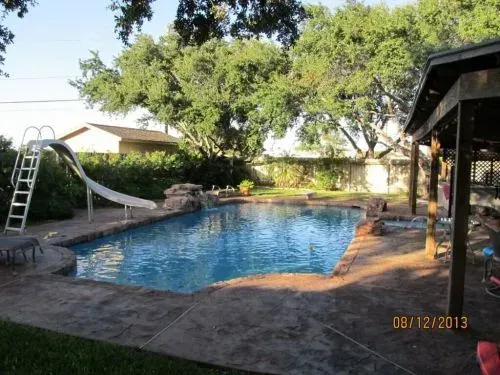 A large swimming pool with a slide in the backyard