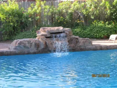 A waterfall is in the middle of a swimming pool.
