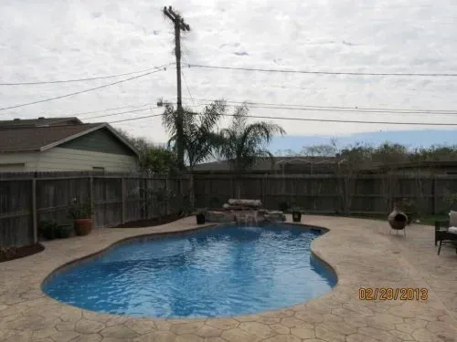 A large swimming pool is in the backyard of a house