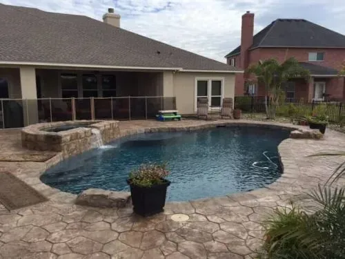There is a large swimming pool in the backyard of a house.