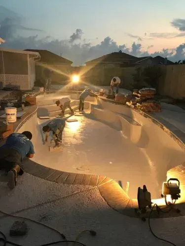A group of men are working on a swimming pool at night.