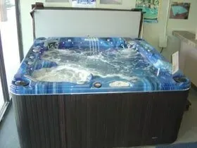 A blue hot tub is sitting in a room next to a window.