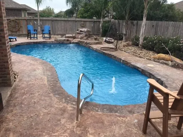 A large swimming pool is surrounded by chairs and a fence.