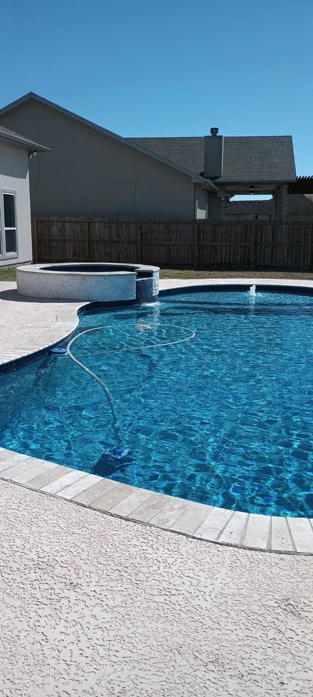 There is a large swimming pool in the backyard of a house.