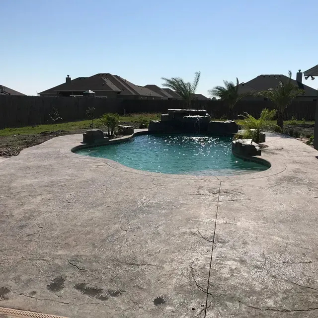 A large swimming pool with a waterfall in the backyard