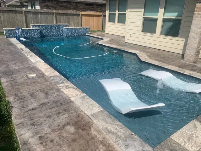 A large swimming pool with two lounge chairs in it.