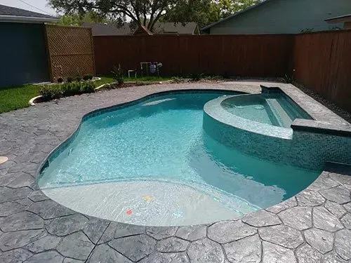 A large swimming pool with a hot tub in the backyard of a house.