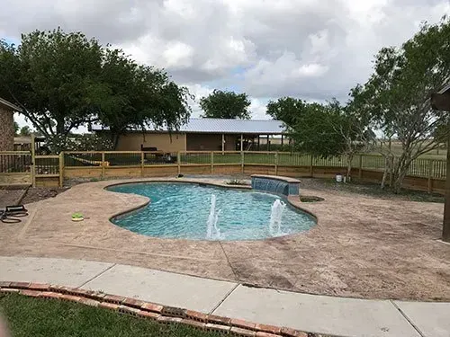 There is a large swimming pool in the backyard of a house.