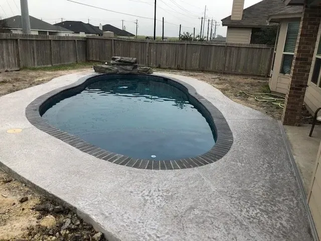 A small swimming pool in the backyard of a house.