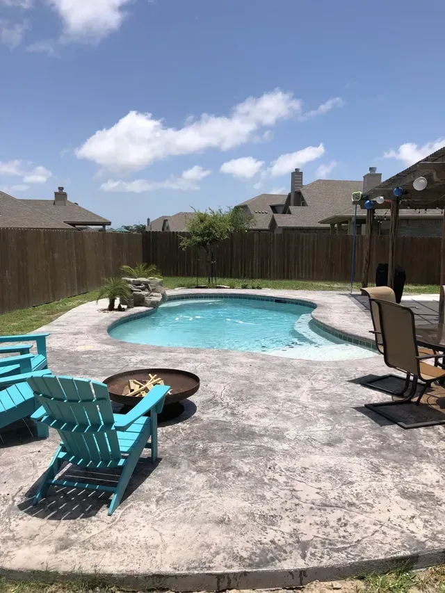 There is a swimming pool in the backyard with chairs and a fire pit.