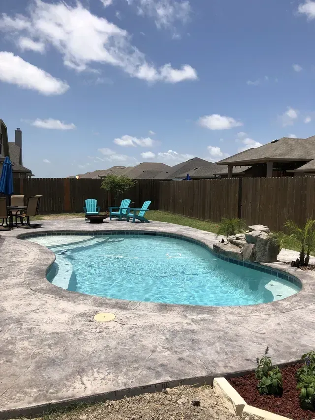 There is a large swimming pool in the backyard of a house.