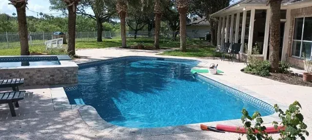 There is a large swimming pool in the backyard of a house.