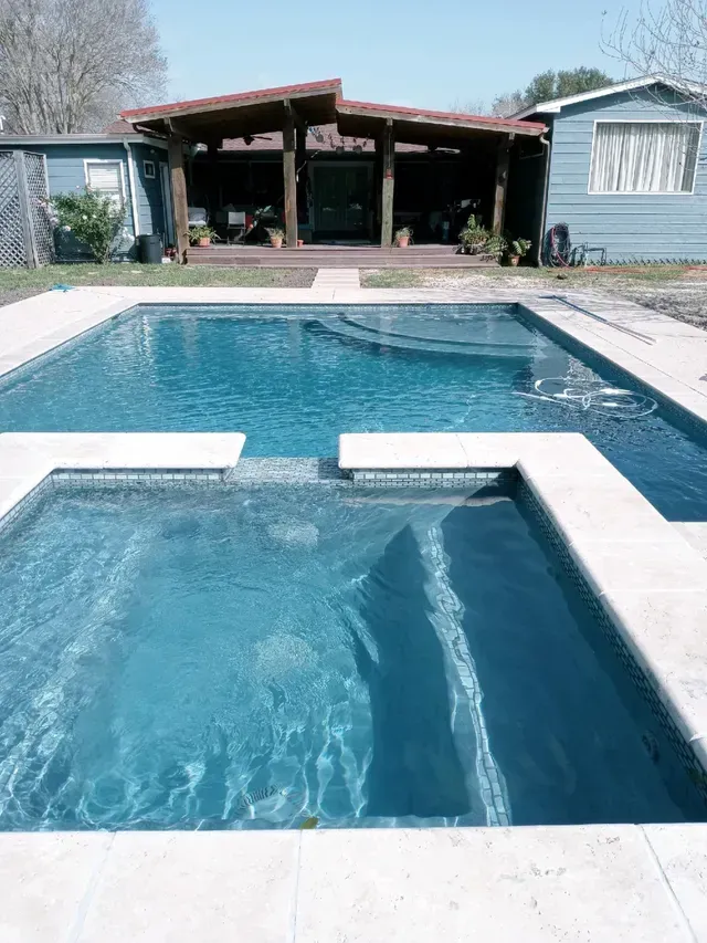 There is a large swimming pool in the backyard of a house.