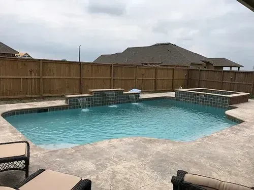 A large swimming pool with a wooden fence surrounding it.