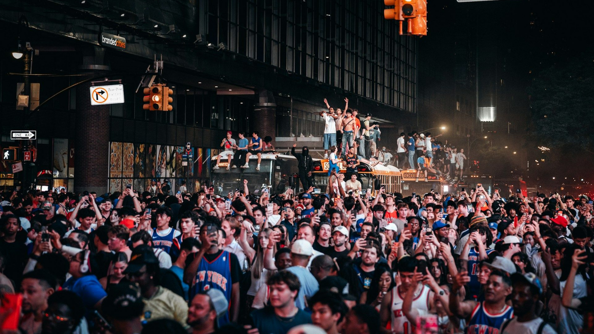 Crowd packed into a city street at night, with raised hands and bright lights during a public celebration