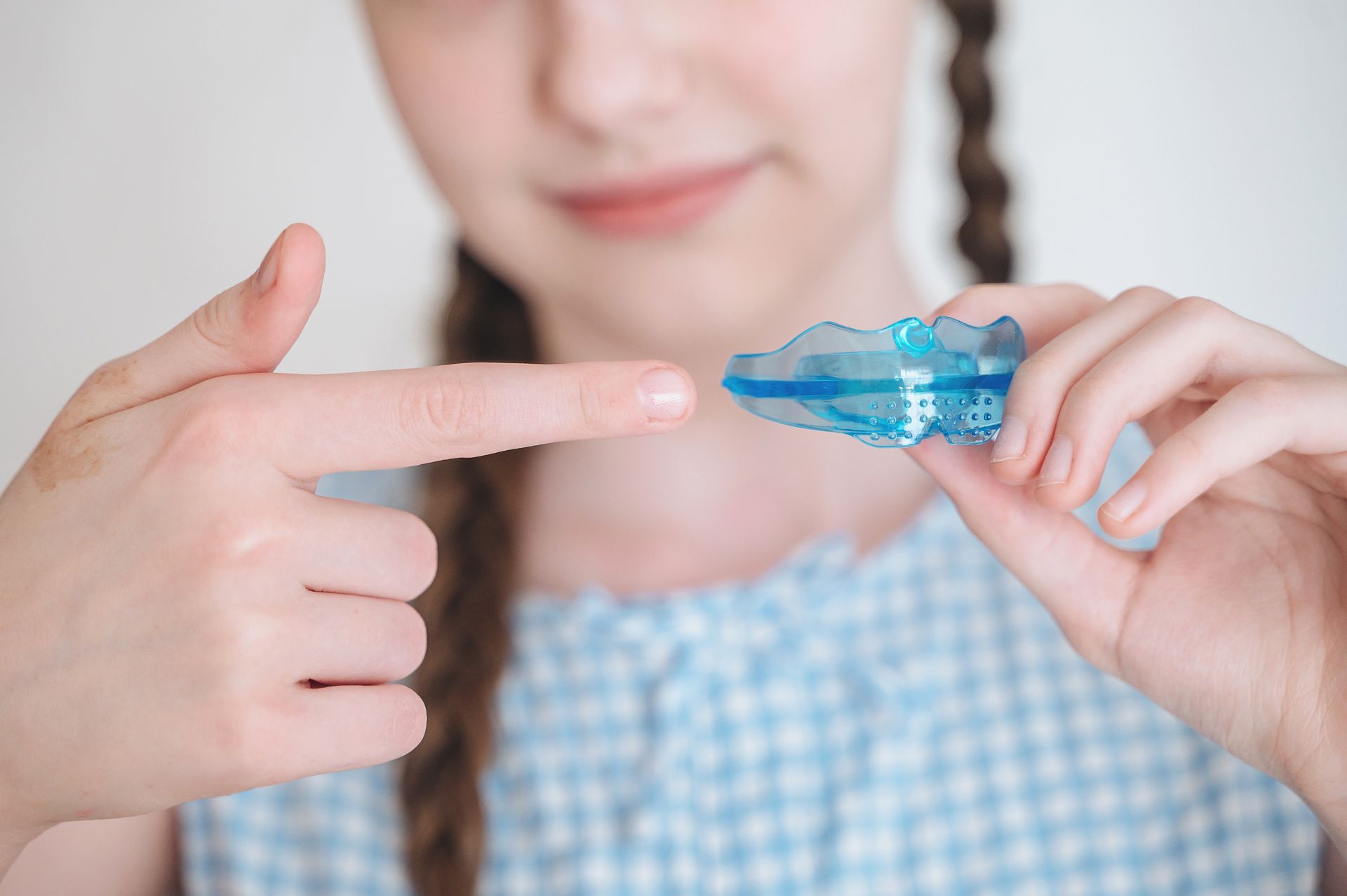 Child holding a blue insulin pen near a finger, preparing to check blood sugar