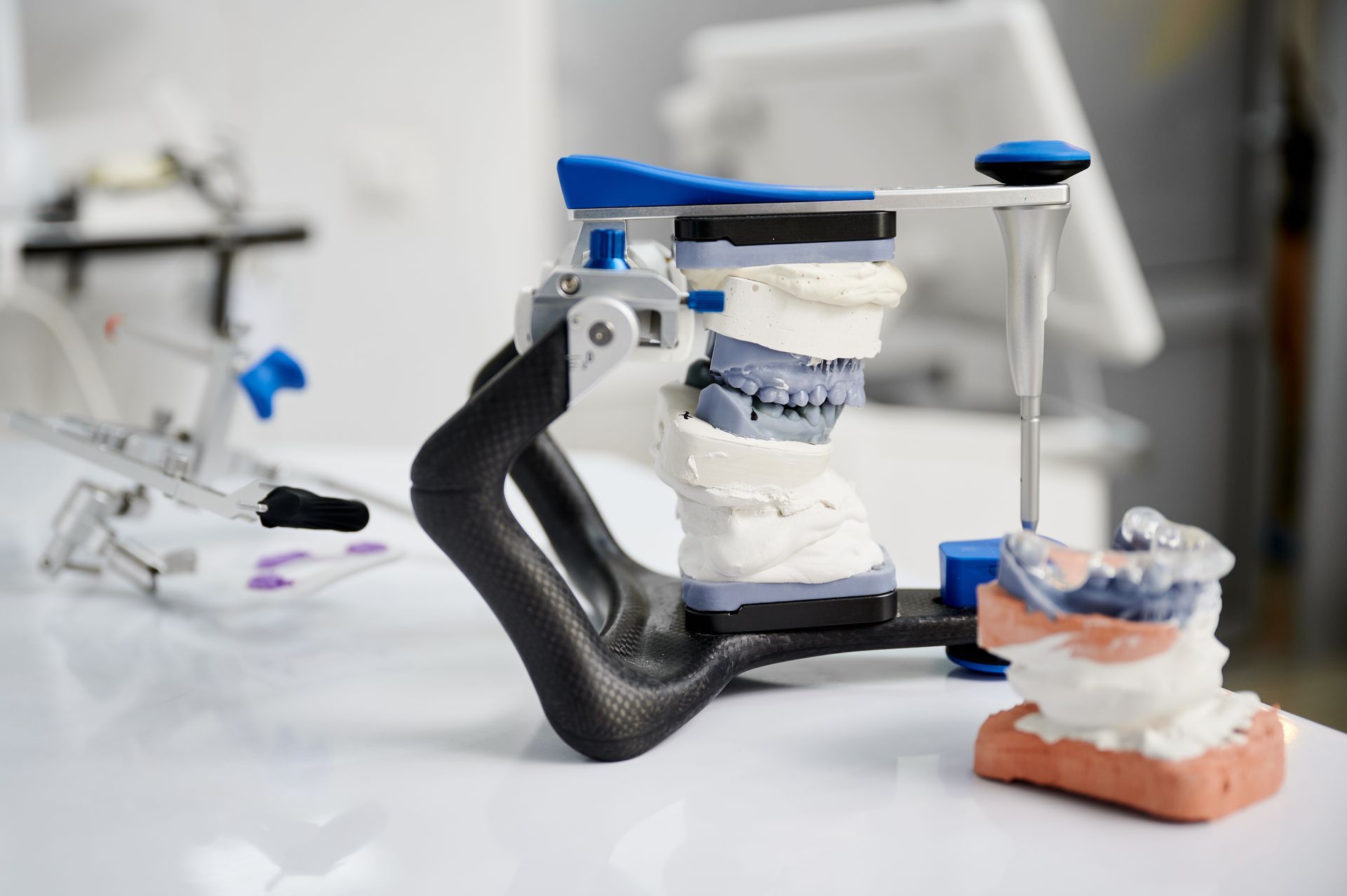Dental model mounted on a clamp, with other dental molds on a white workbench