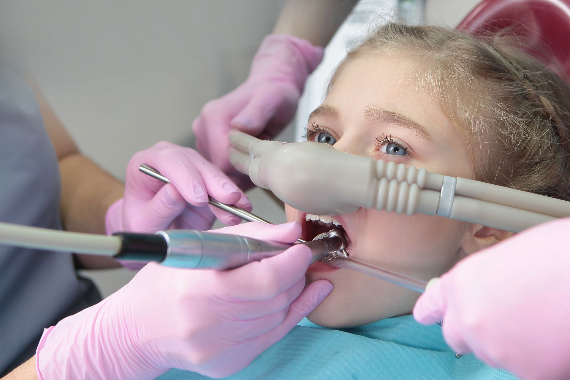 Dentist using tools to examine a child’s teeth in a dental chair
